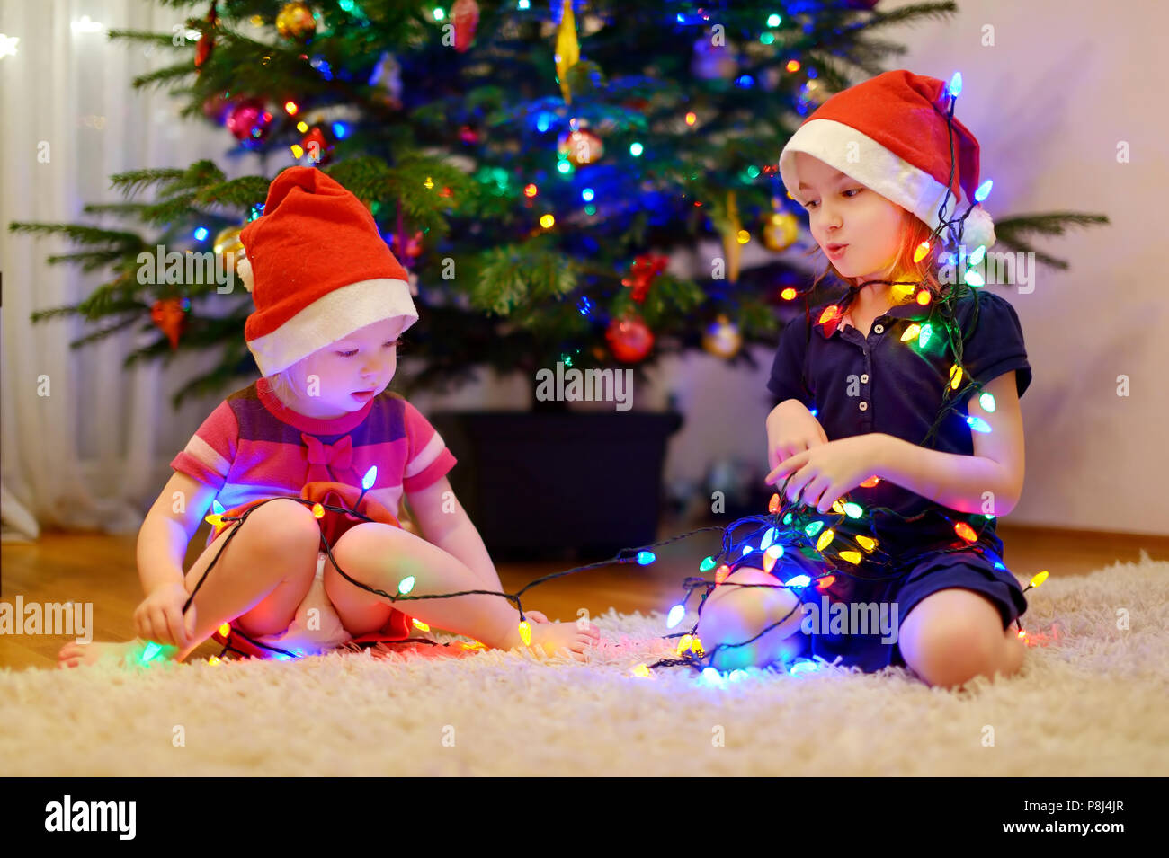Two adorable little sisters decorating a Christmas tree at home Stock ...