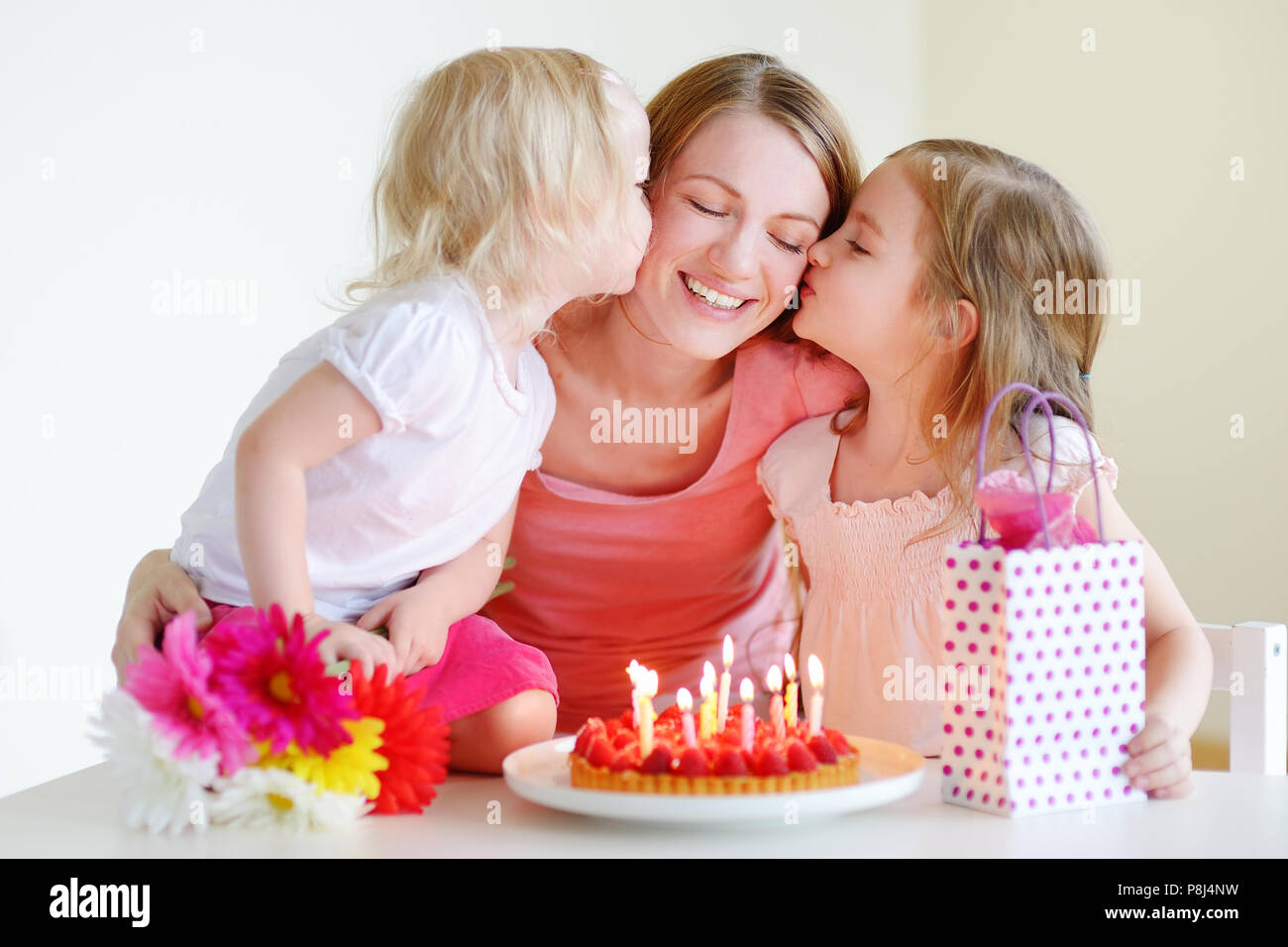 two-little-daughters-kissing-their-mother-wishing-her-a-happy-birthday