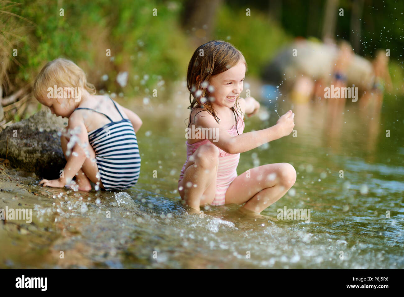 Two little sisters wearing swimsuits having fun in a river at summer Stock Photo Alamy