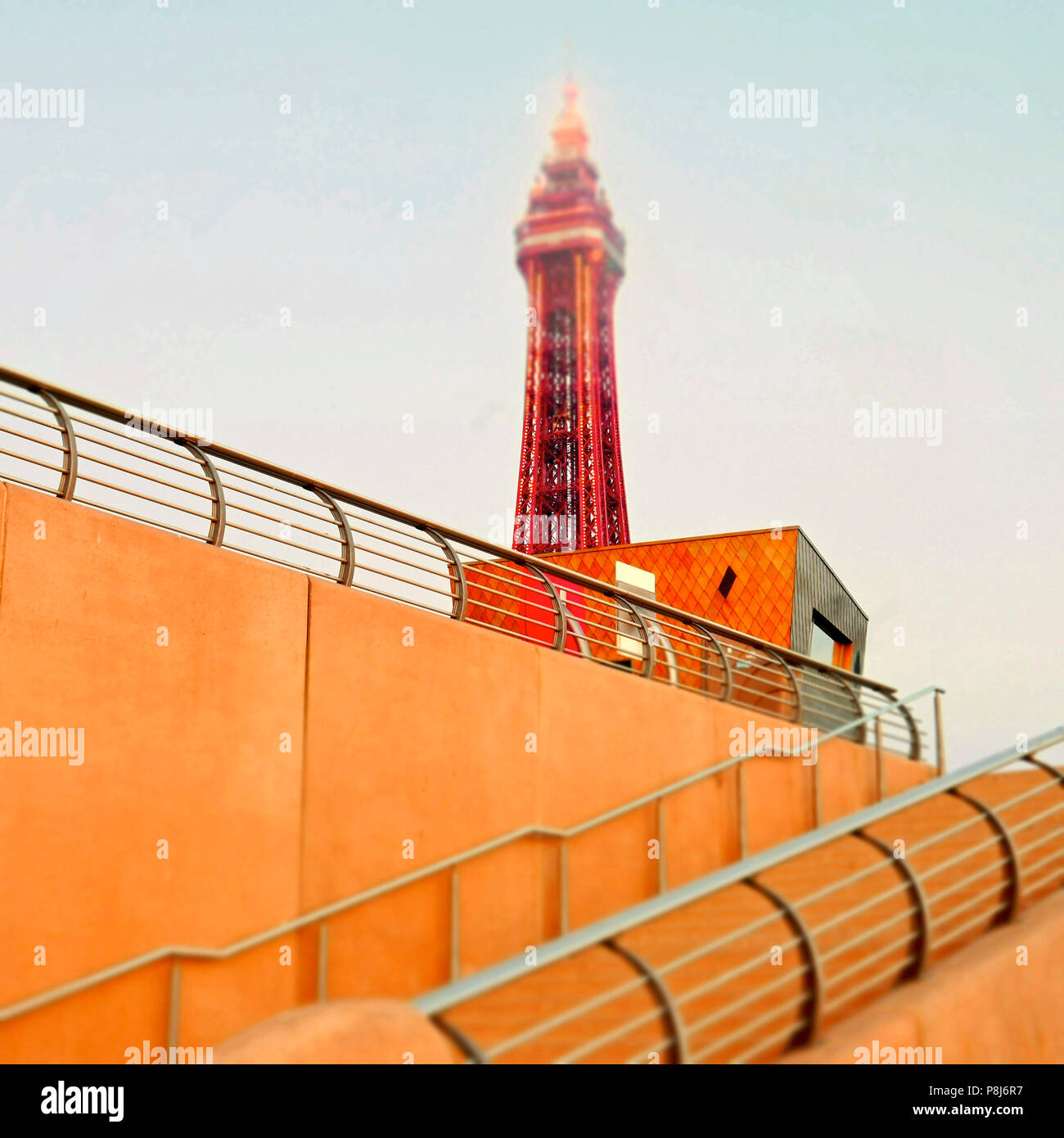 Blackpool Tower shining at dusk above concrete steps leading down from the seafront Stock Photo