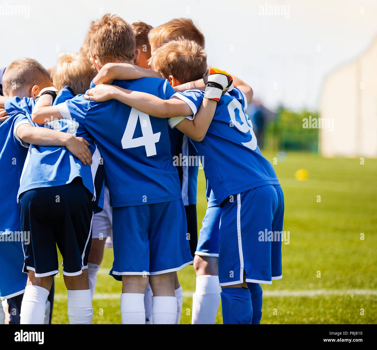 Boys sports team with coach. Youth soccer team huddle with coach. Motivation talk, pep talk before the match. Young football soccer players in jersey  Stock Photo