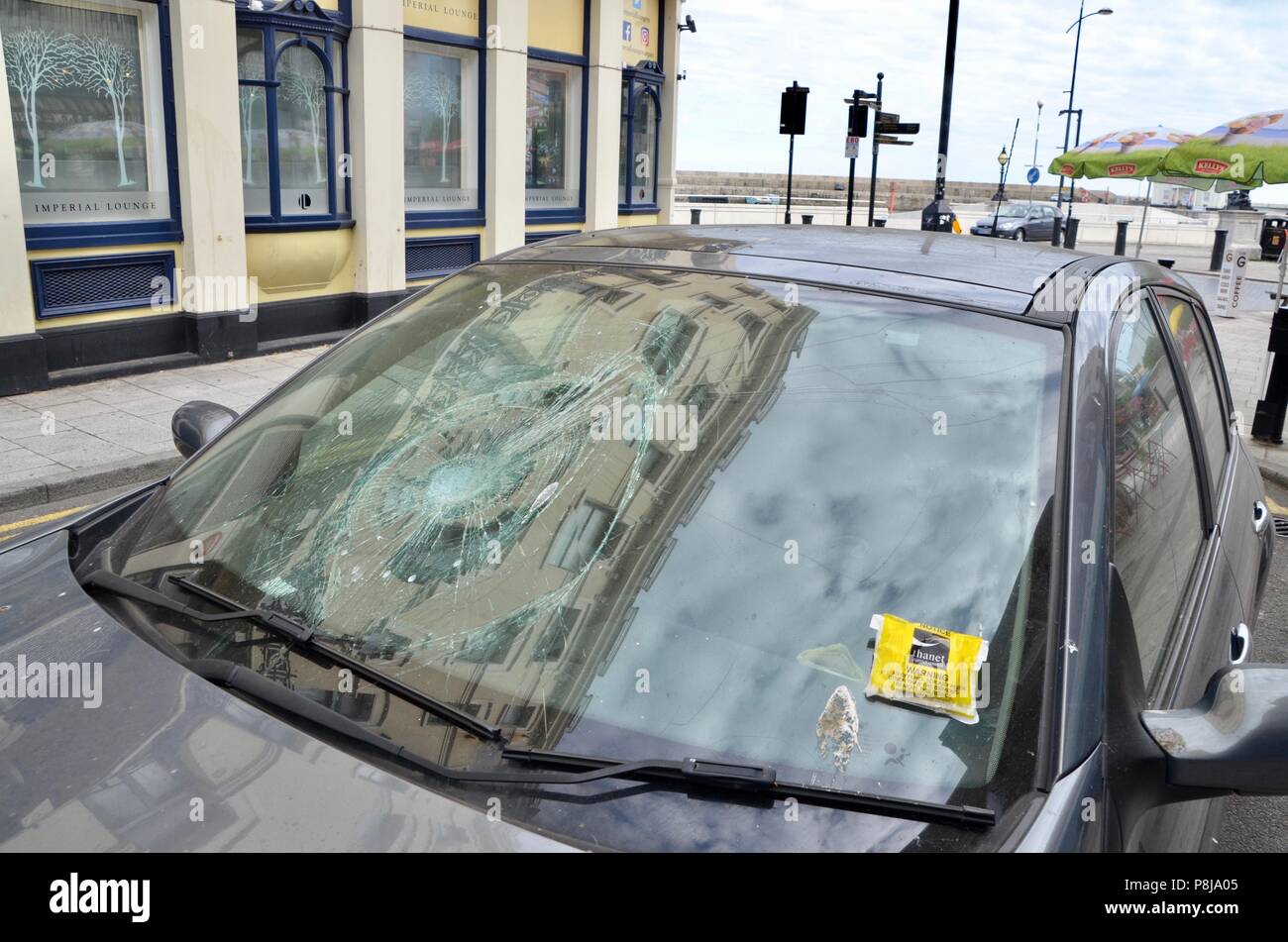 a car with a smashed windscreen and parking ticket in margate side street kent UK Stock Photo