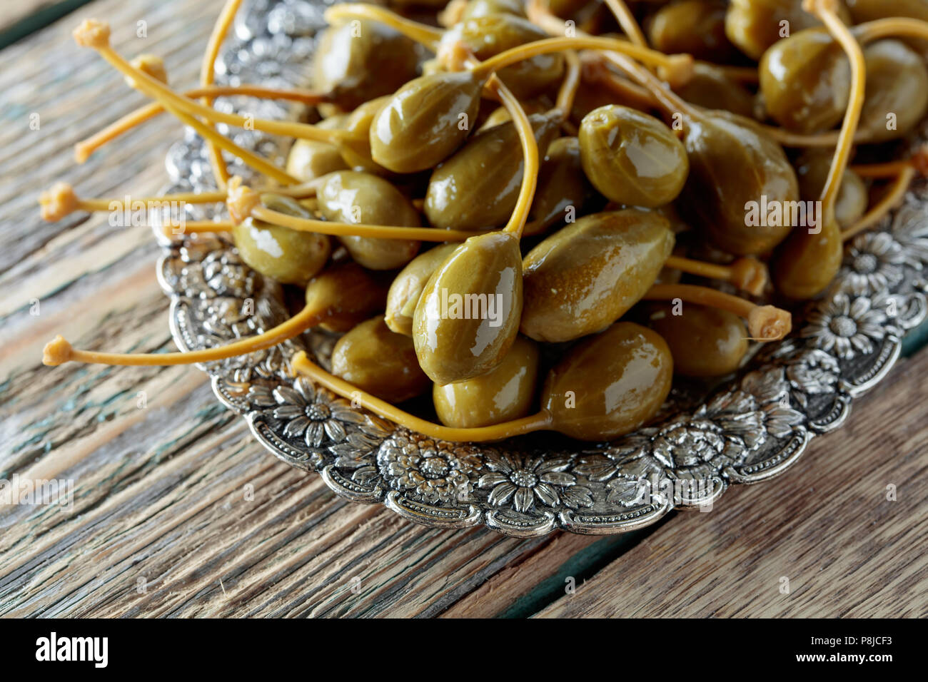 Pickled caper berries in metal dish . Edible fruits of Capparis