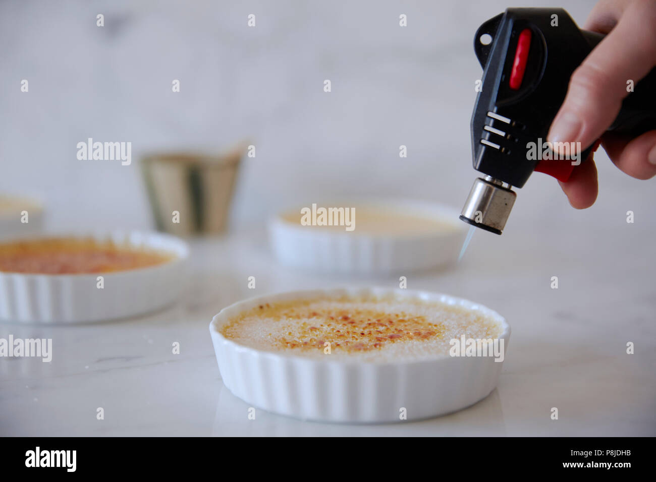 Melting sugar on a creme brûlée with a blow torch Stock Photo Alamy