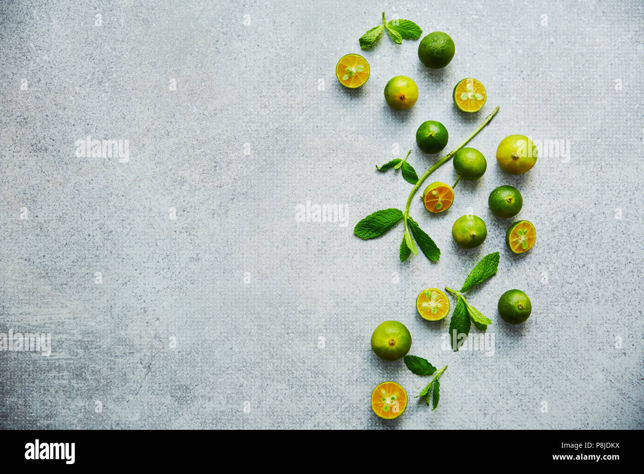 Green calamondin on grey background. Horizontal food background, top view Stock Photo