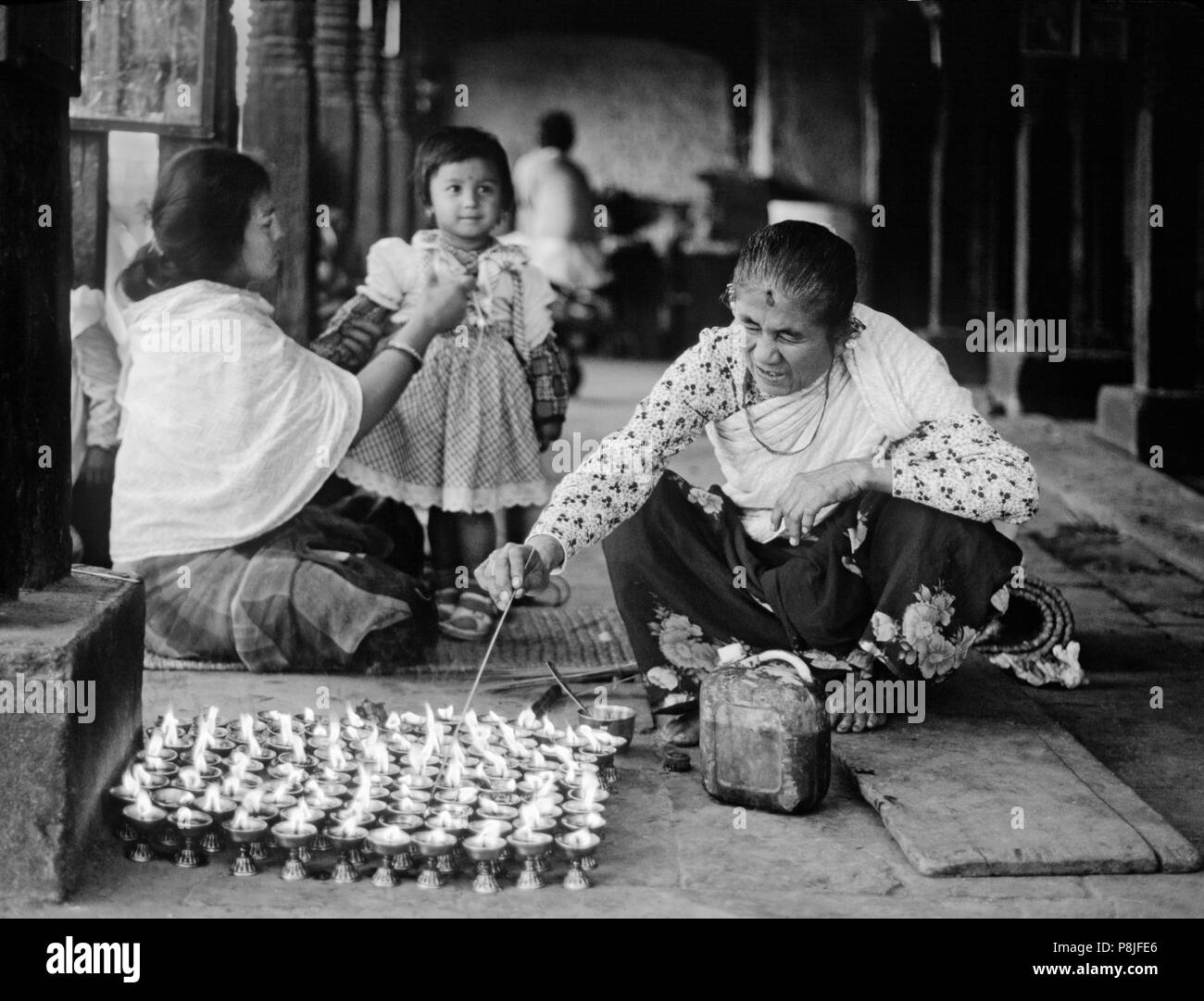 A NEWARI woman lights PUJA CANDLES at SWAYAMBUNATH STUPA - KATHAMANDU, NEPAL Stock Photo