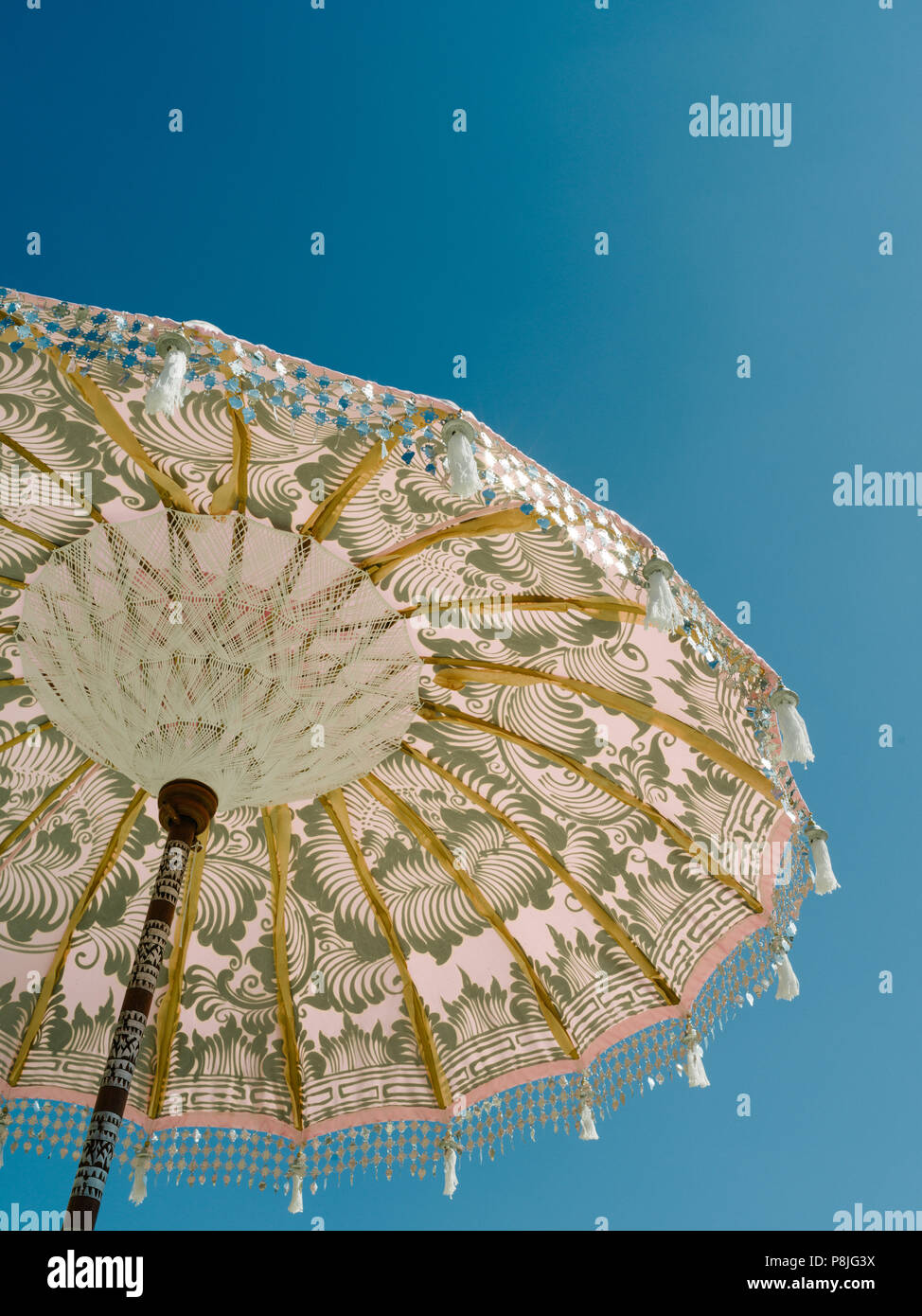 pink hassled modern umbrella in the summer sun against bright blue sky English summer Stock Photo
