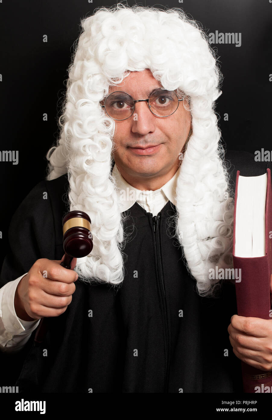 Portrait Of Male Lawyer Holding Judge Gavel And Book on black Stock Photo