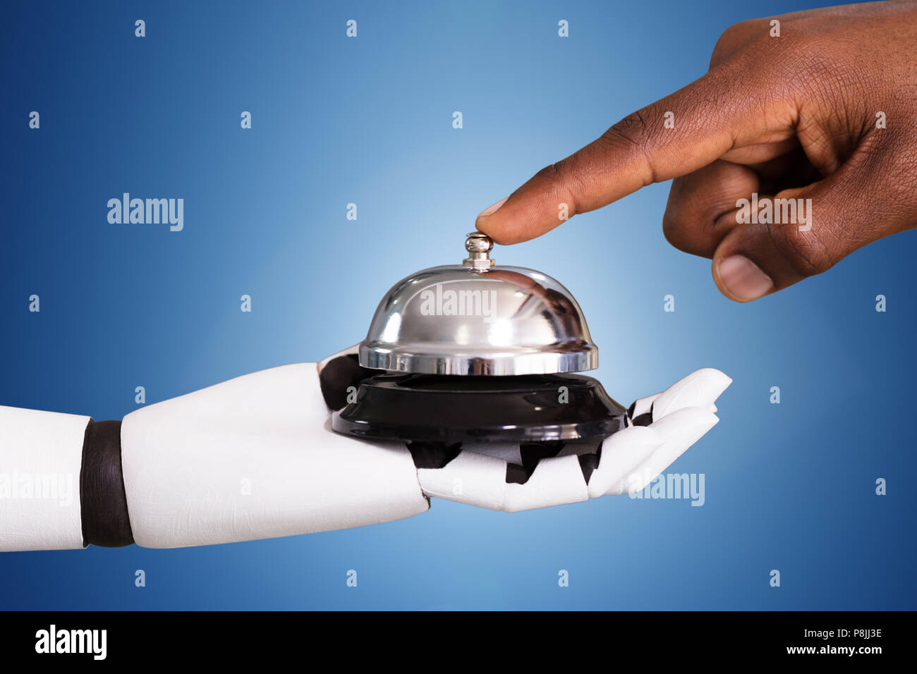 Close-up Of A Person Ringing Service Bell Hold By Robot Against Blue Background Stock Photo