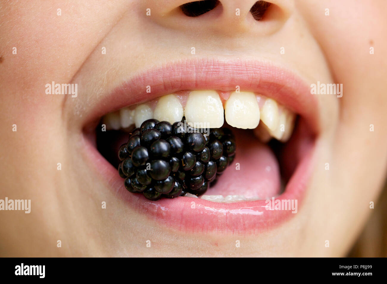 Girl eating a Blackberry Stock Photo