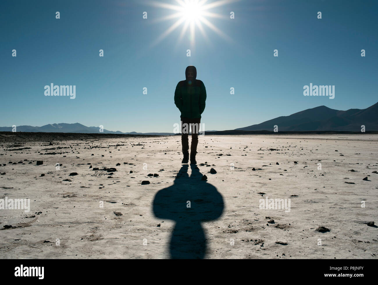 Silhouette of a man walking on the deserted, surreal landscape of Salar de Chiguana, Bolivia, South America Stock Photo