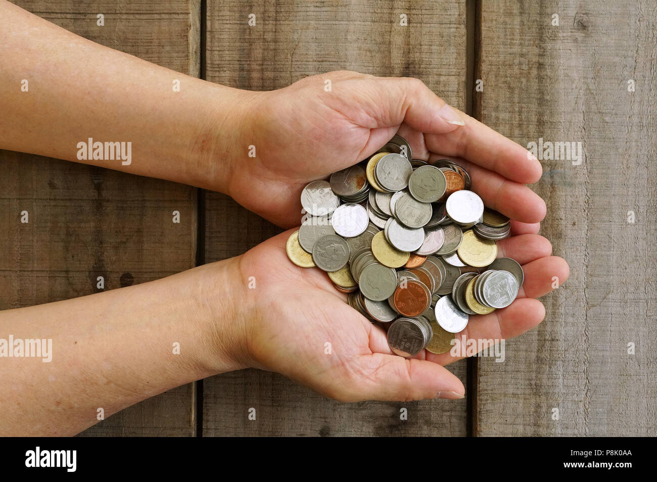 Two hands carry coin money with wood background.finance concept Stock