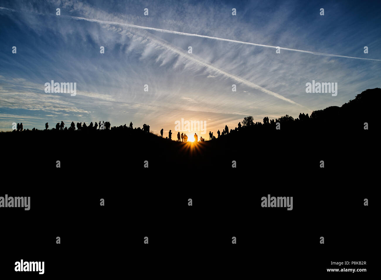 A crowd silhouetted on top of a hill at Avebury for the Summer Solstice Stock Photo