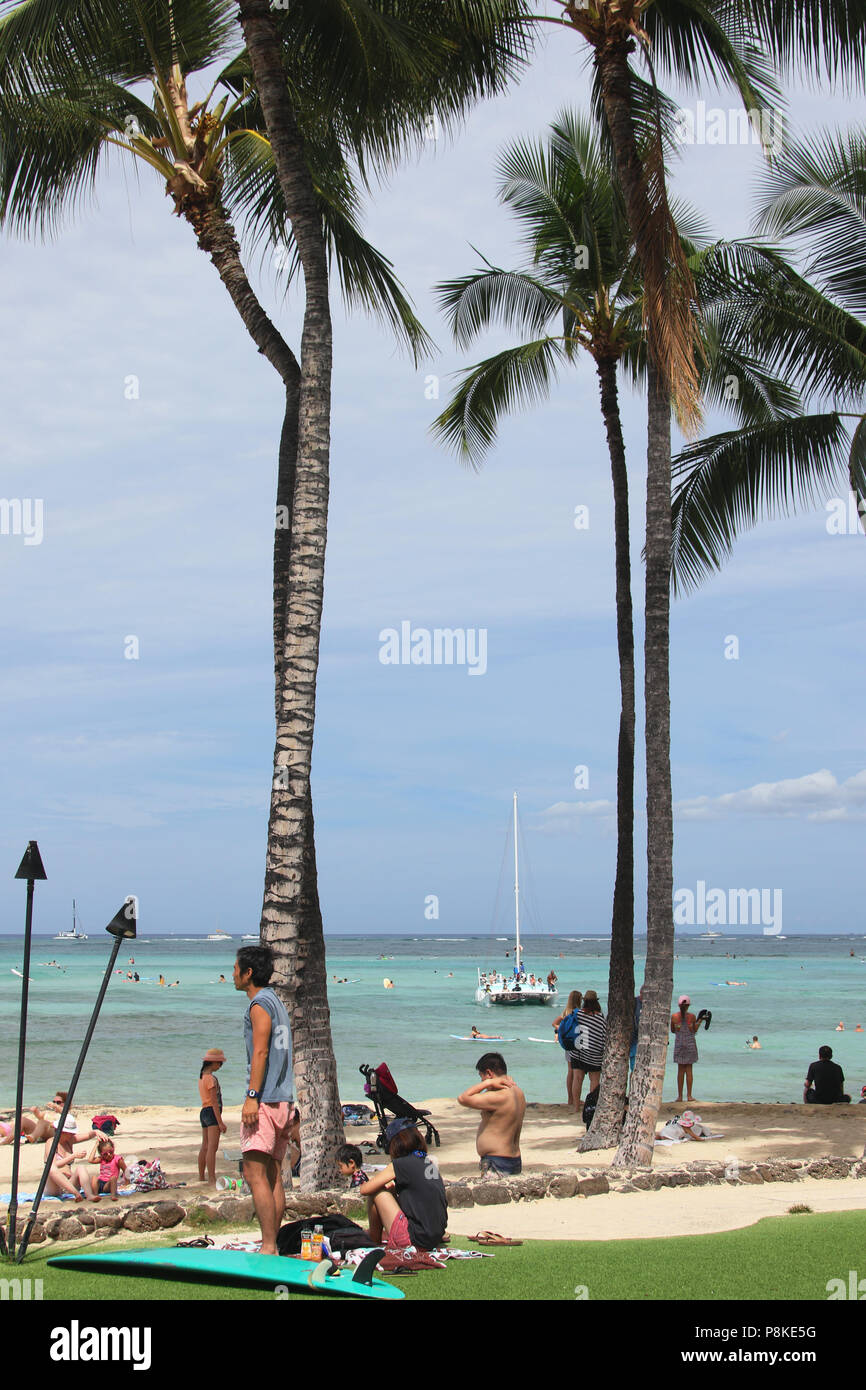 Tourists on the beach. Tourist sailboat named Mana Kai is visible