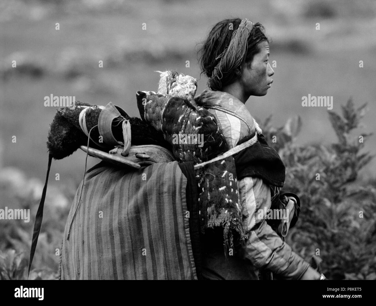 A TIBETAN KAMPA (nomad) carries a horse SADDLE on his back in the DO TARAP VALLEY - DOLPO, NEPAL Stock Photo