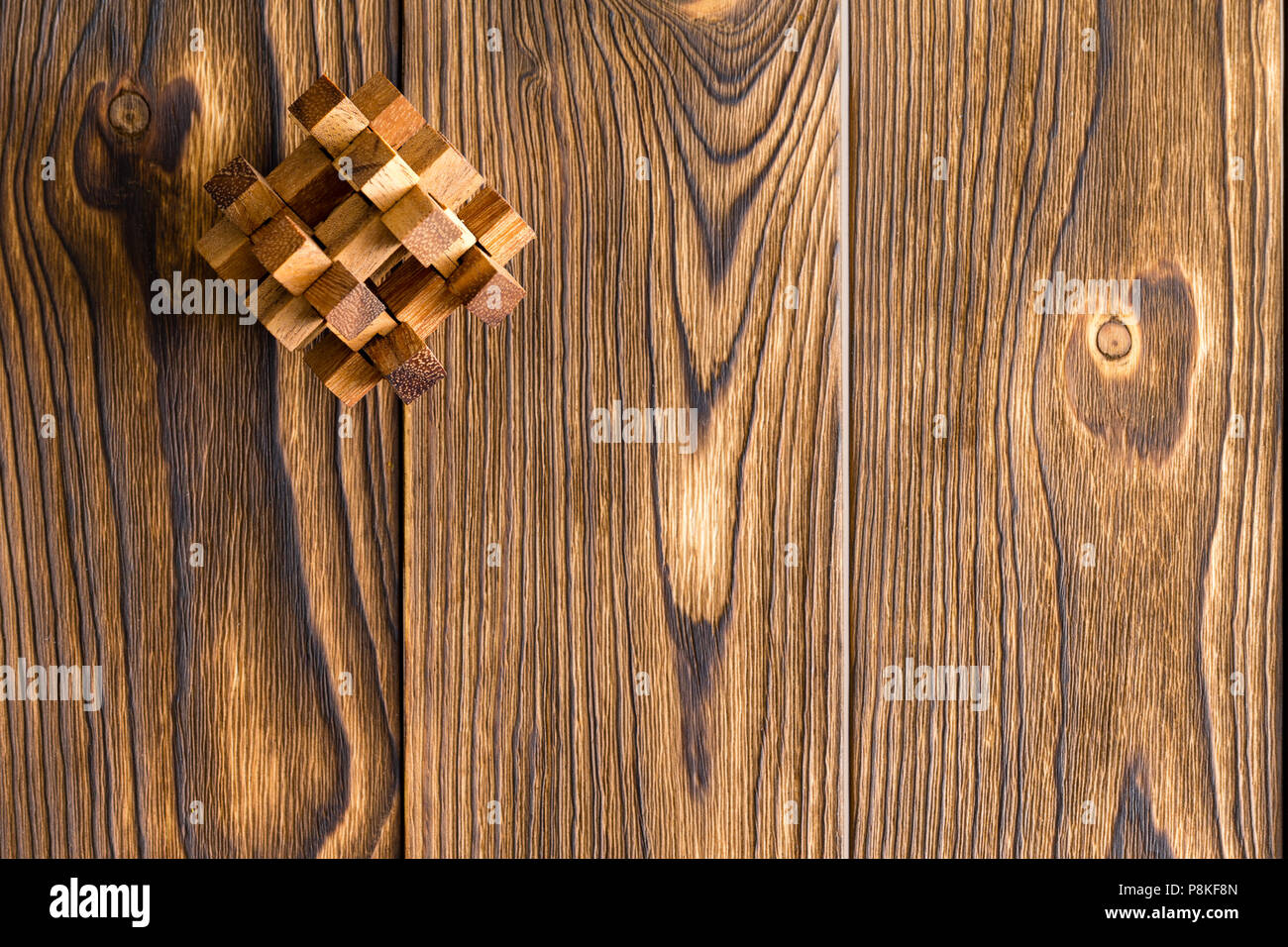 Intricate interlocked wooden puzzle in the corner on a textured wood background with woodgrain and copy space Stock Photo