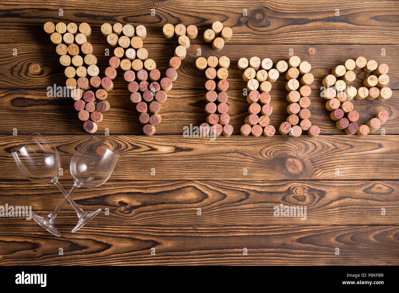 Wine lettering made of corks with two glasses against wooden background Stock Photo