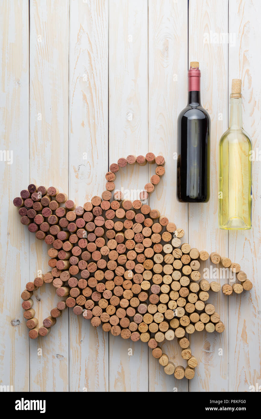 Creative marine turtle design of used wine corks with two full bottles of red and white wine on a textured white wood background with copy space viewe Stock Photo