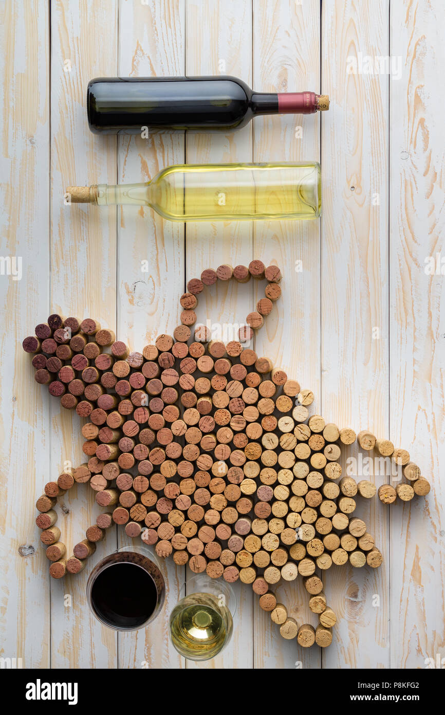 Marine turtle composed of wine corks and two unlabeled bottles of red and white wine concept, viewed overhead, on light wooden background Stock Photo