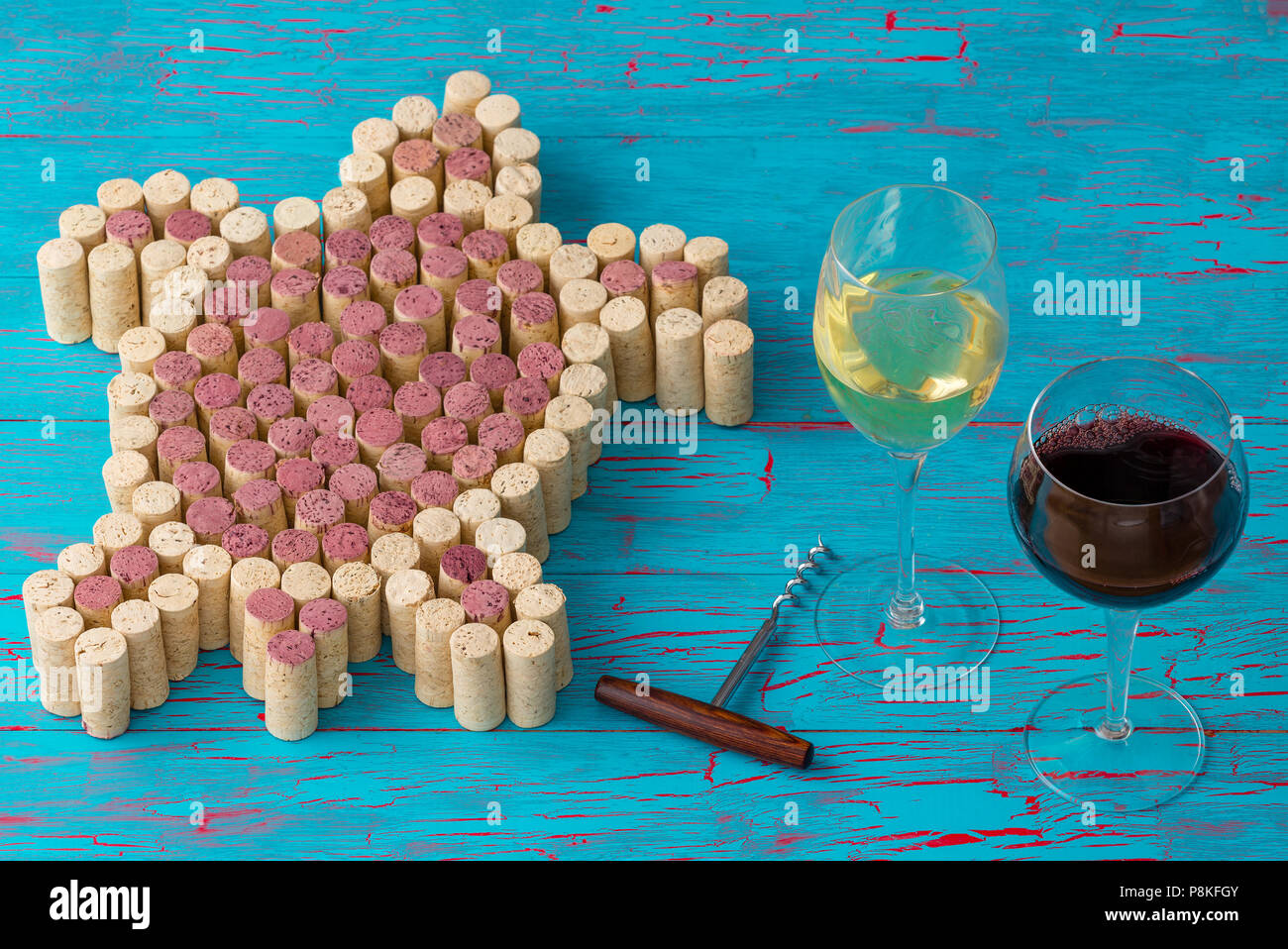 Creative design of a sea turtle from red and white wine bottle corks on a textured turquoise blue wood background with glasses of wine and a corkscrew Stock Photo