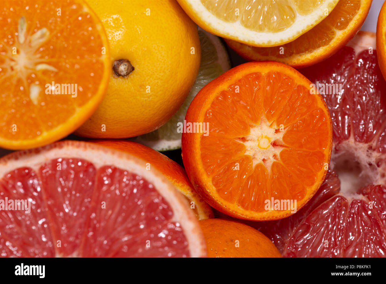 Close up on juicy fresh cut citrus fruits with rose grapefruit, orange, lemon and clementines in a full frame view Stock Photo