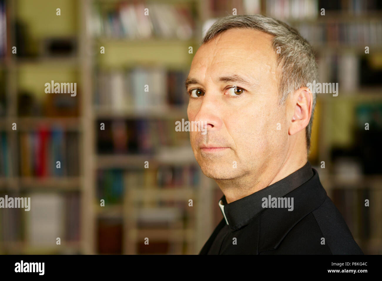 A portrait of a good looking worried catholic priest.  He looks at us with interest, pensiveness, proselytising, trust and seriousness and concernness Stock Photo