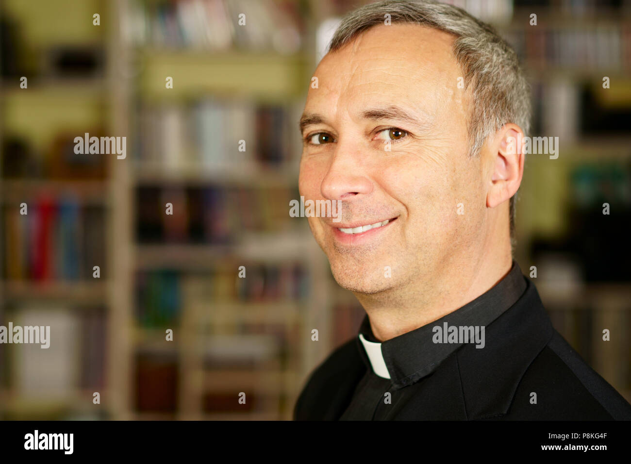 A portrait of a good looking serious catholic priest.  He looks at us with interest, pensiveness, proselytising, joy, happyness, trust and peacefulnes Stock Photo