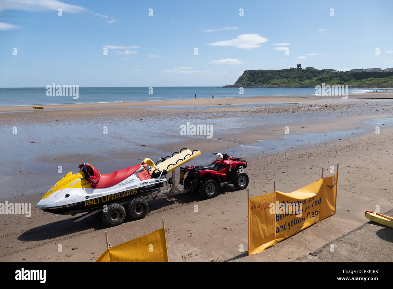 Lifeguard Emergency vehicles parked with beach warning signs on the beach at North Bay, Scarborough,UK with the castle and cliffs in the  distance. Stock Photo