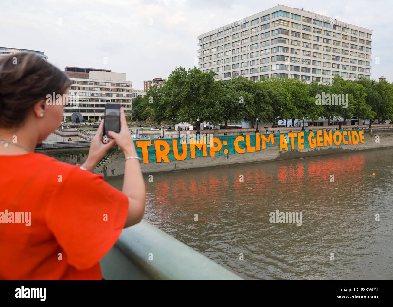 Westminster, London, 12th July 2018. Campaigners against climate change protest over Donald Trump's visit by dropping a giant banner reading 'Trump: Climate Genocide' at St Thomas’ Hospital Gardens, opposite the Houses of Parliament in Westminster. The huge banner, 100 metres x 9 metres large, is to raise awareness about the US president's climate policies. Credit: Imageplotter News and Sports/Alamy Live News Stock Photo