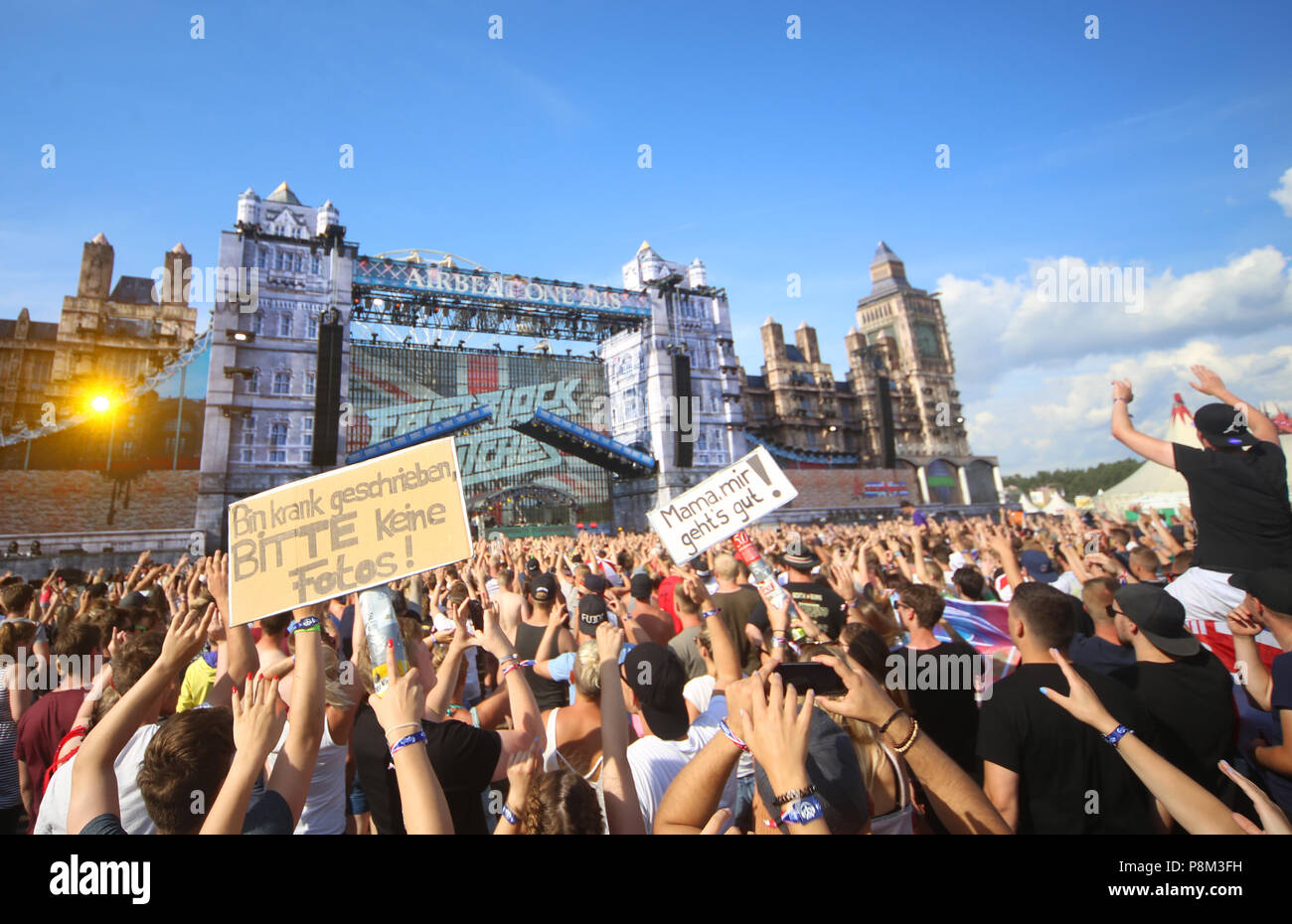 12 July 2018, Germany, Neustadt-Glewe: Visitors holding up signs at the electro music festival 'Airbeat One' with the phrases 'bin krank geschrieben, bitte keine Fotos' (lit. I called in sick, no photos please) and 'Mama, mir geht's gut' (lit. I'm OK mum). The festival started on Wednesday with the motto 'Great Britain'. Up to 55,000 visitors are expected to attend each day. Around 170 Djs and artists will be providing a varied line-up until it's finish on Sunday at 8am. Photo: Danny Gohlke/dpa-Zentralbild/dpa Stock Photo