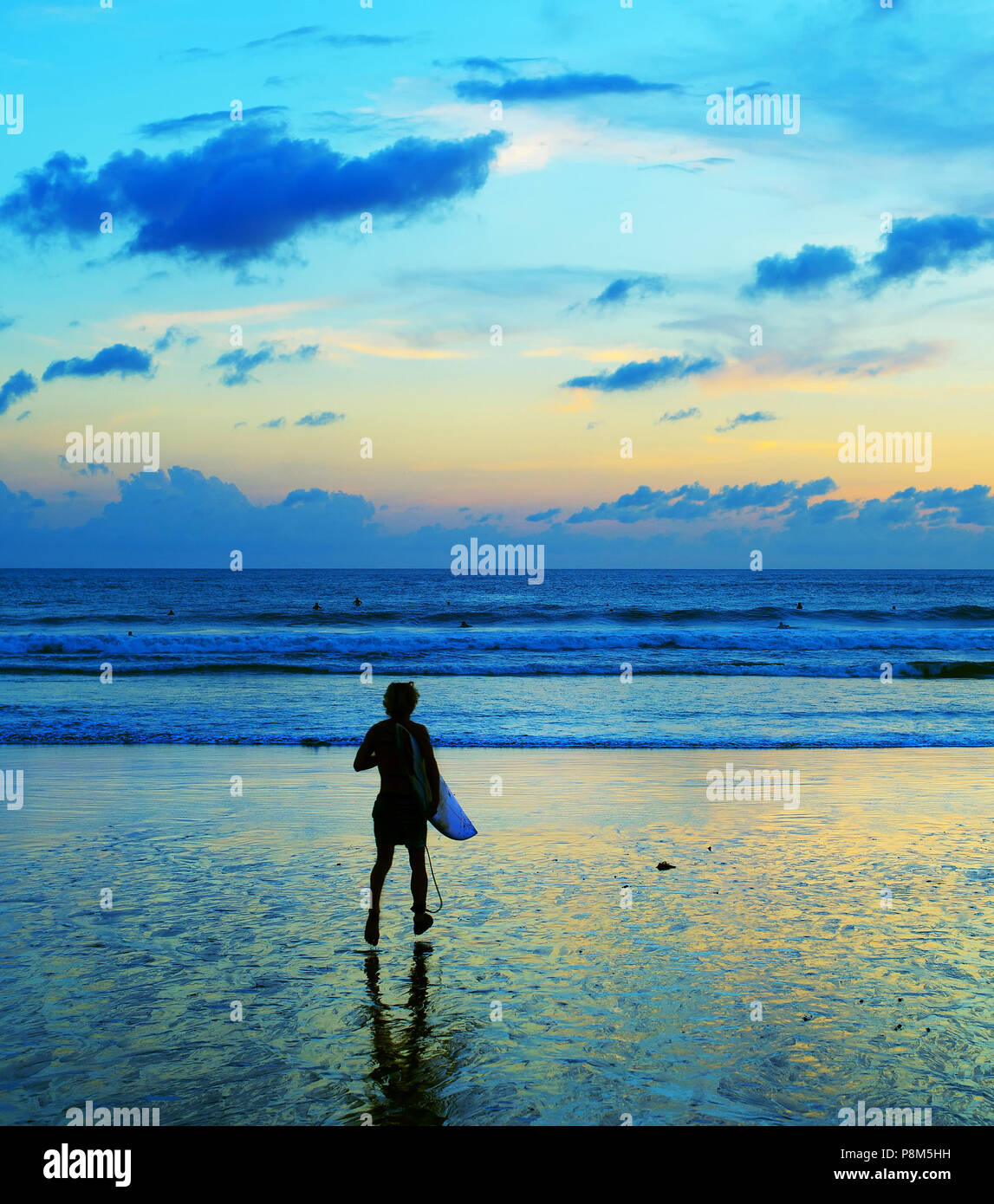 Surfer hurry up to surf in the ocean at sunset. Bali island, Indonesia Stock Photo