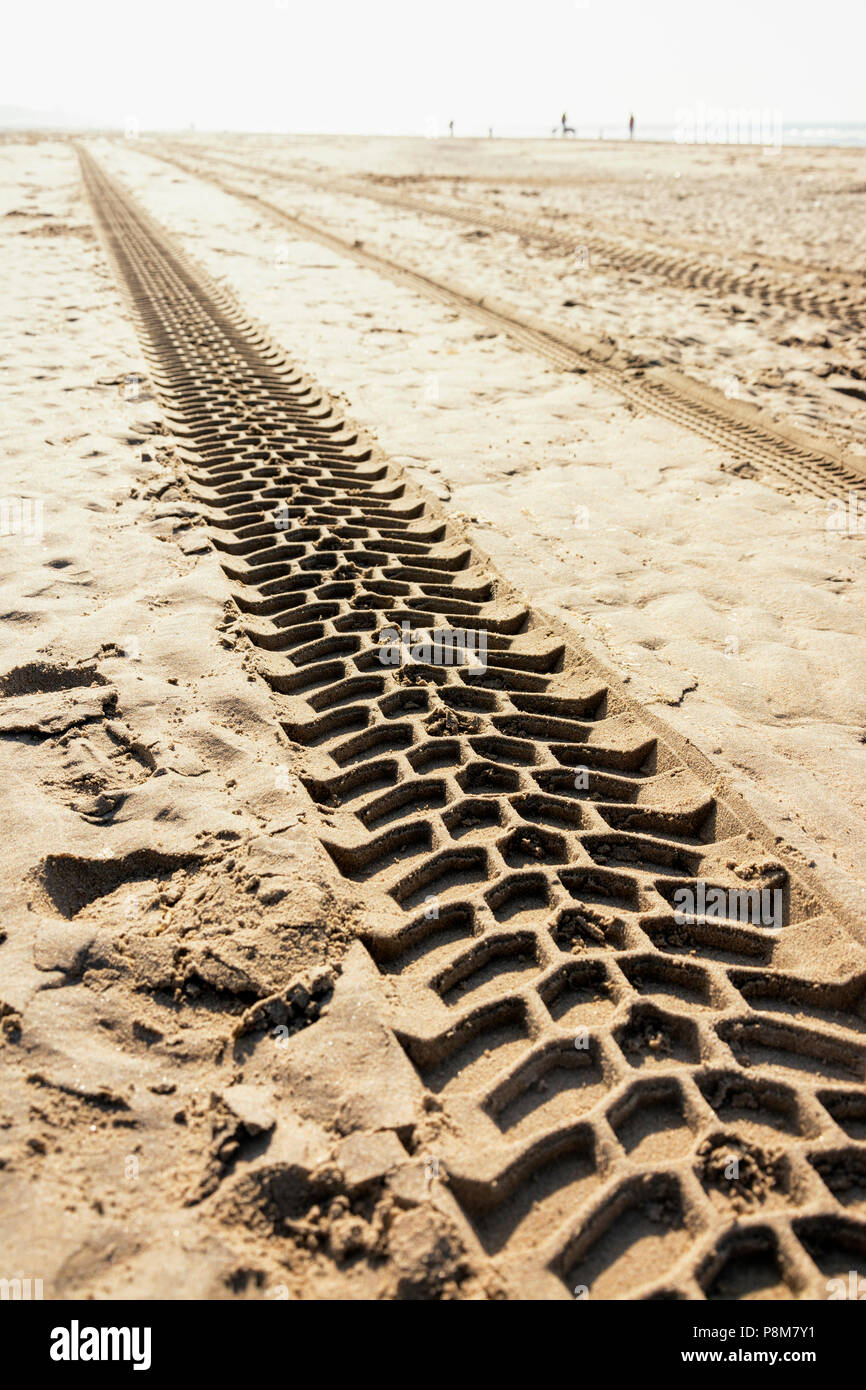 View on tracks of tyres of a motorised vehicle on the beach, manmade patterns and structuresin the sand Stock Photo