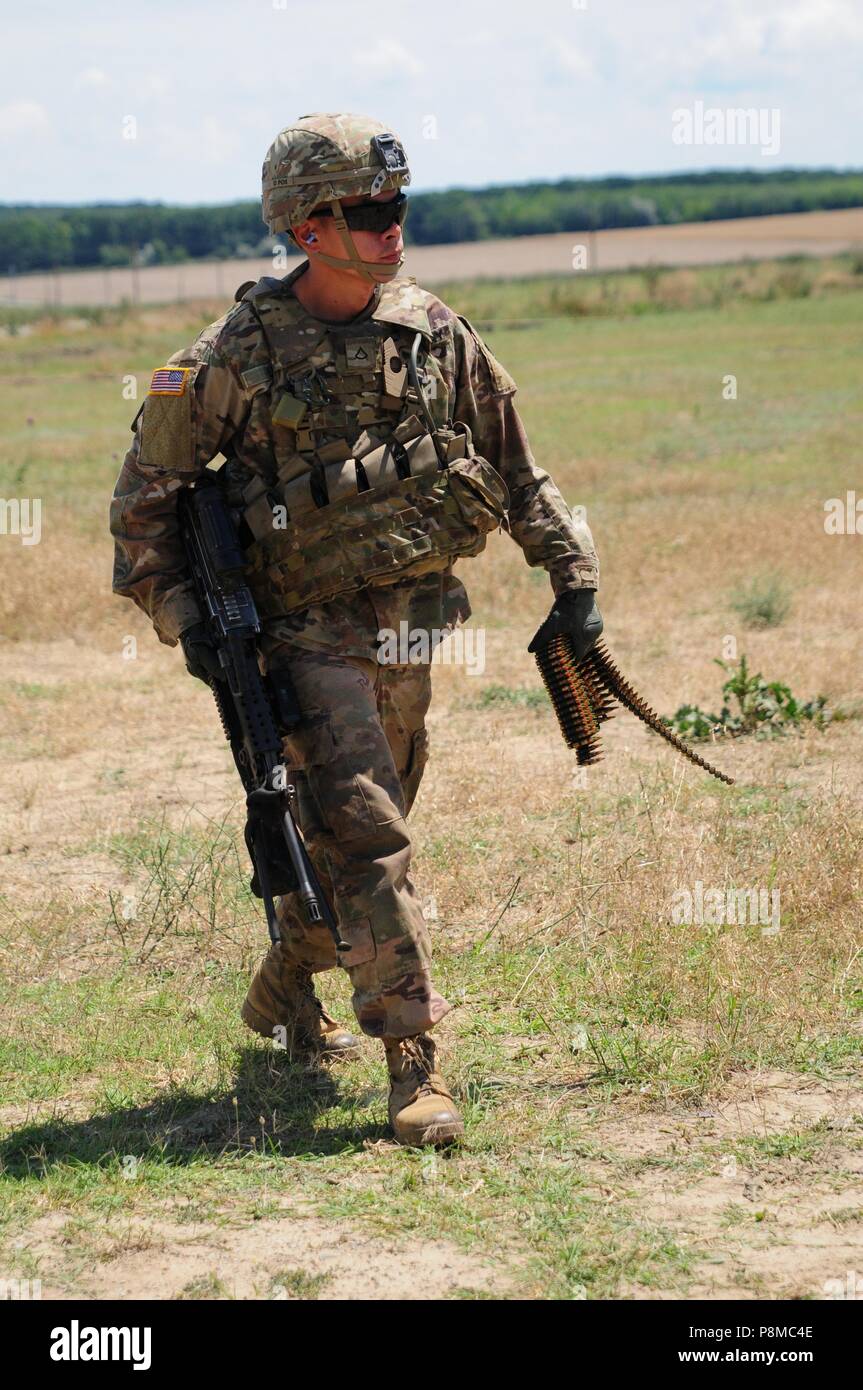 Army Pfc. Shuang Li, assigned to Bravo Company, 2-5 Cav, 1st Armored Brigade Combat Team, 1st Cavalry Division, walks to the Bravo Zulu Range in Romania, Mihail Kogalniceanu Air Base, June 25, 2018, June 25, 2018. Li shot a multitude of targets with an M249B machine gun during a small arms fire training exercise in support of Atlantic Resolve, an enduring training exercise between NATO and U.S. Forces. (U.S. Army National Guard photo by Spc. Hannah Tarkelly, 382nd Public Affairs Detachment/ 1st ABCT, 1st CD/Released). () Stock Photo