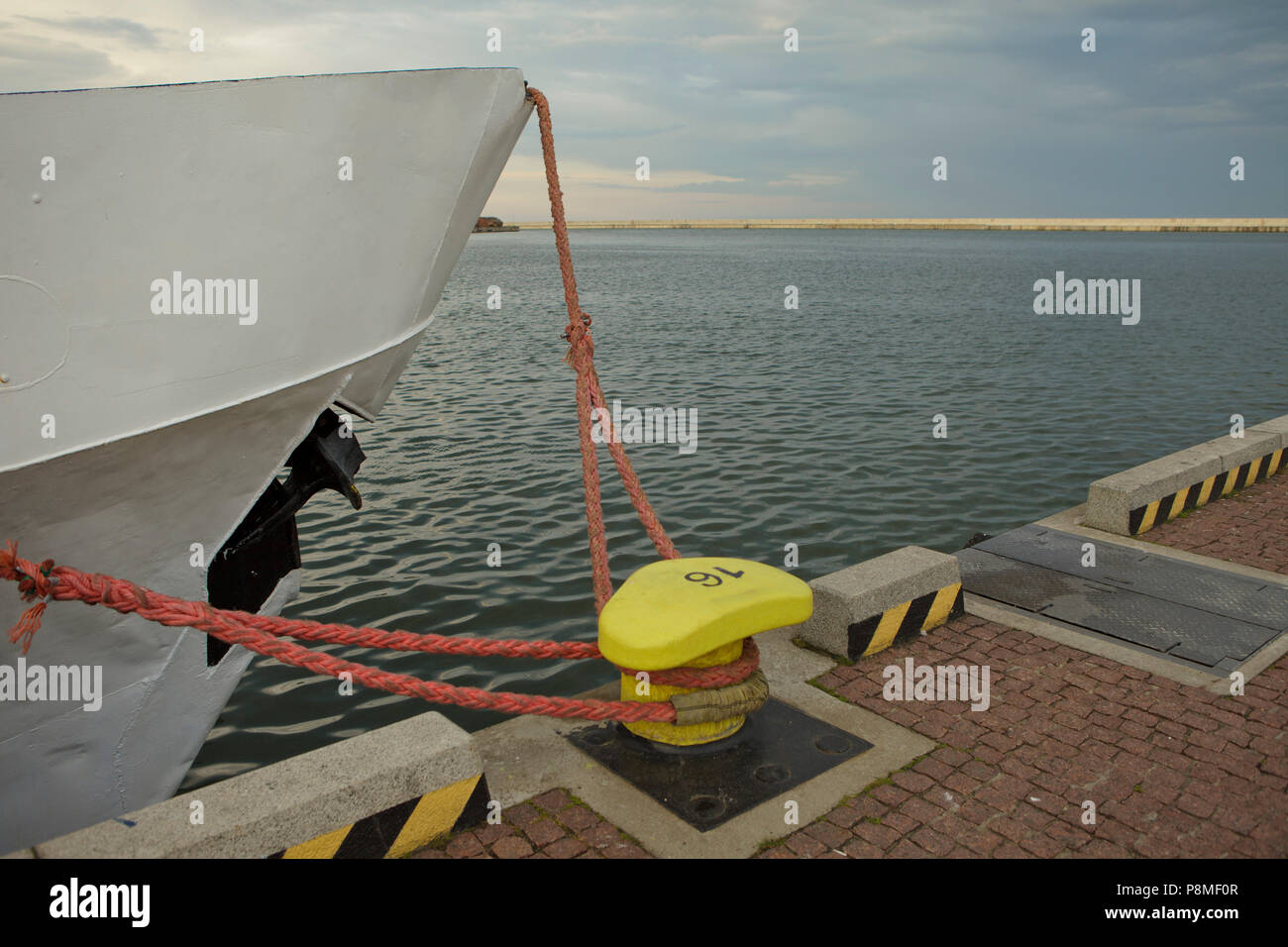 front part of ship and yellow mooring in sea harbour, cloudy summer