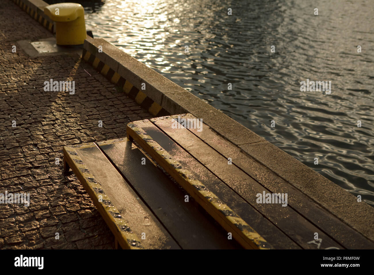concrete pier with little steps and yellow mooring in evening summer light Stock Photo