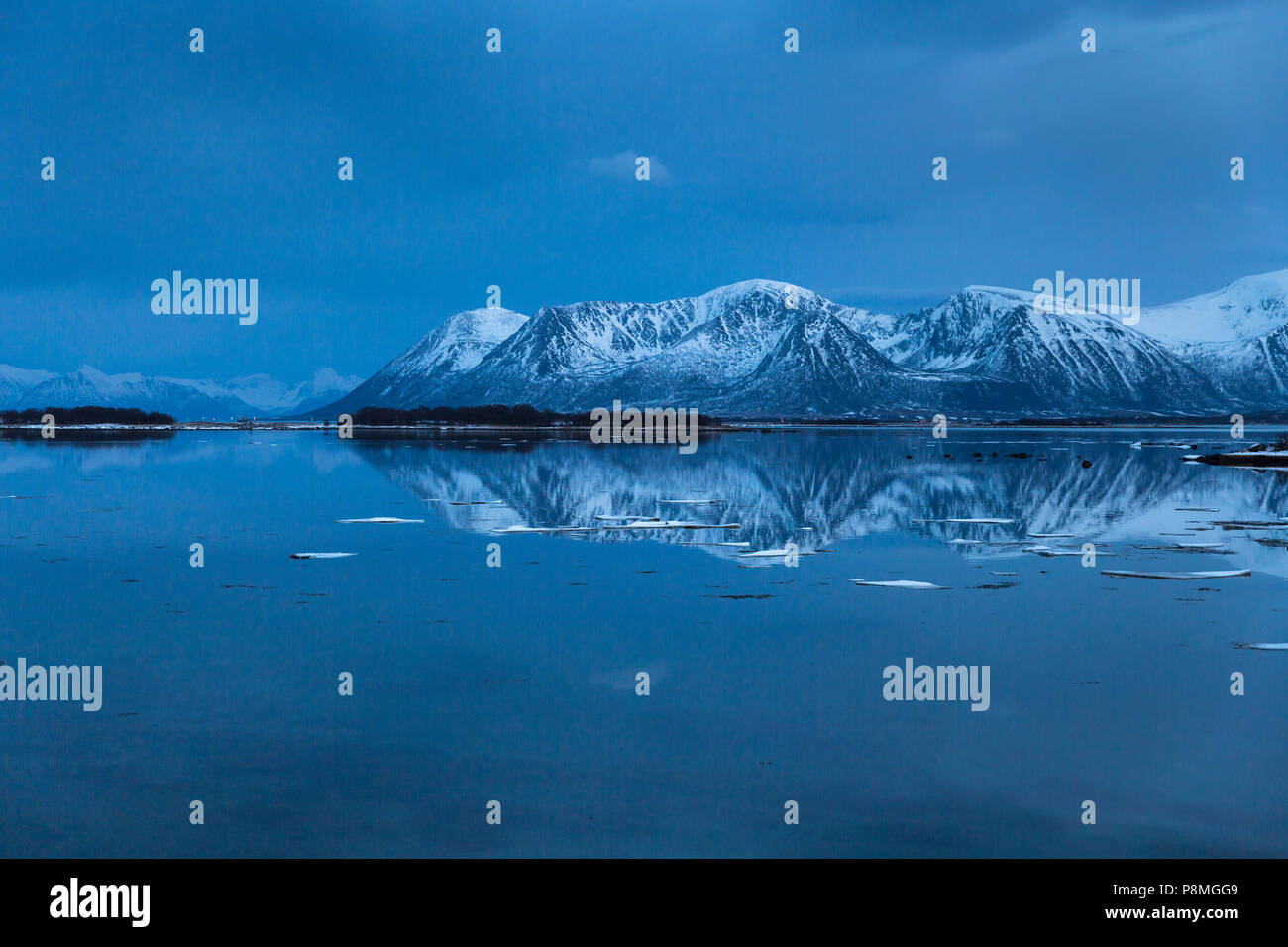 Snow-covered mountains reflecting in a lake after sunset Stock Photo