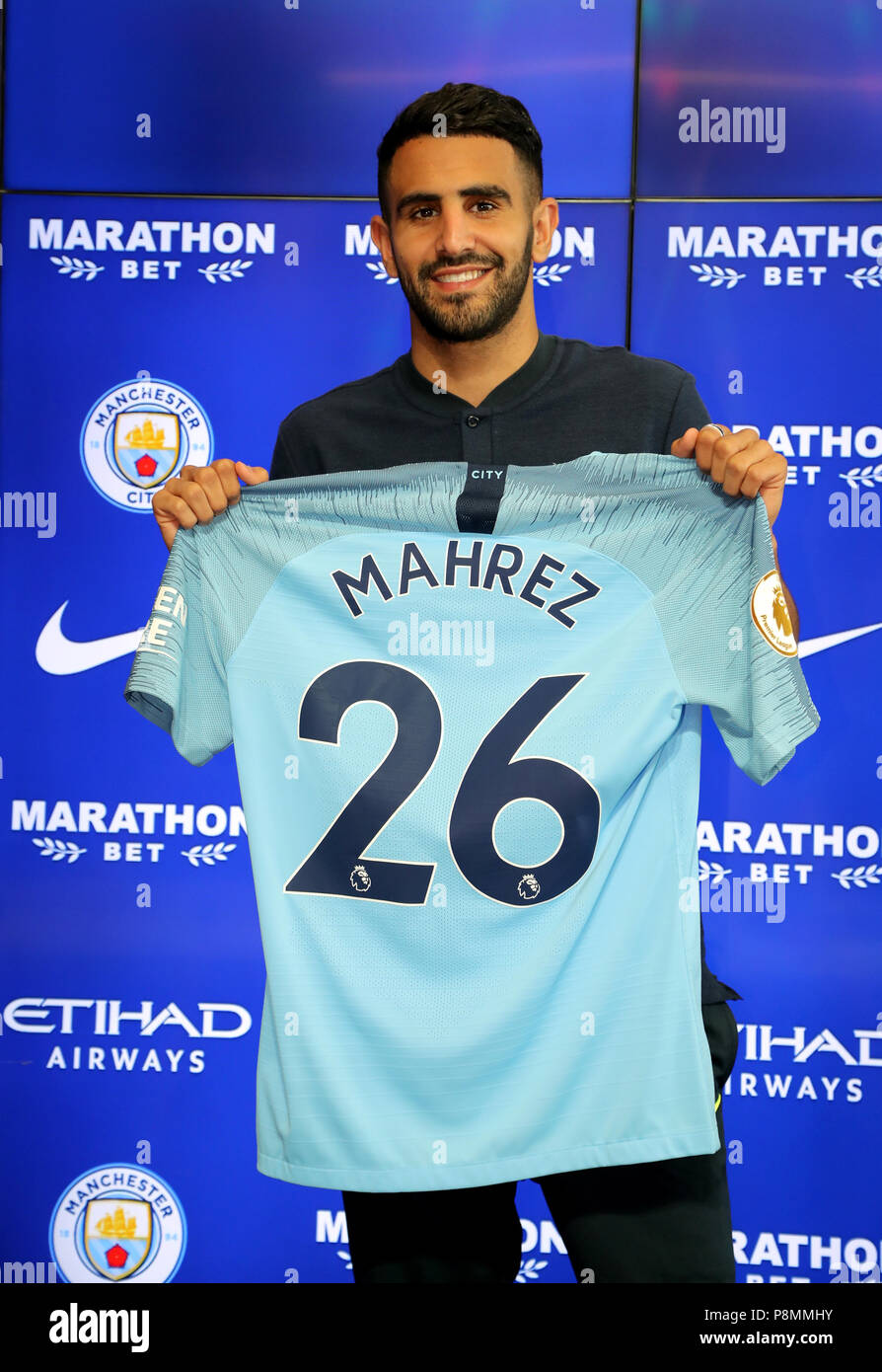 New Manchester City signing Riyad Mahrez holds up his shirt during the press conference at the City Football Academy, Manchester. Stock Photo