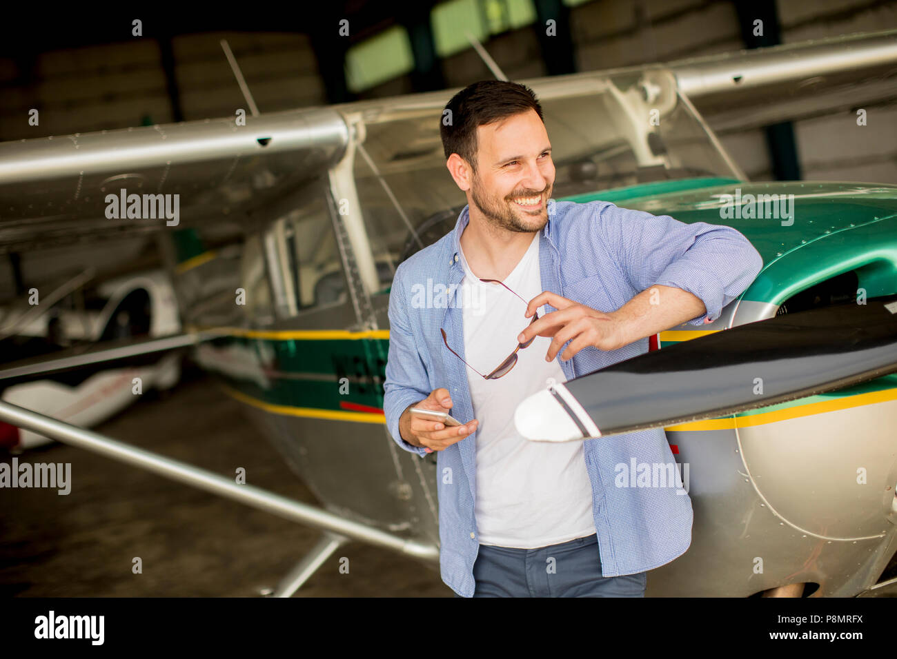 Handsome young pilot checking airplane  in the hangar Stock Photo