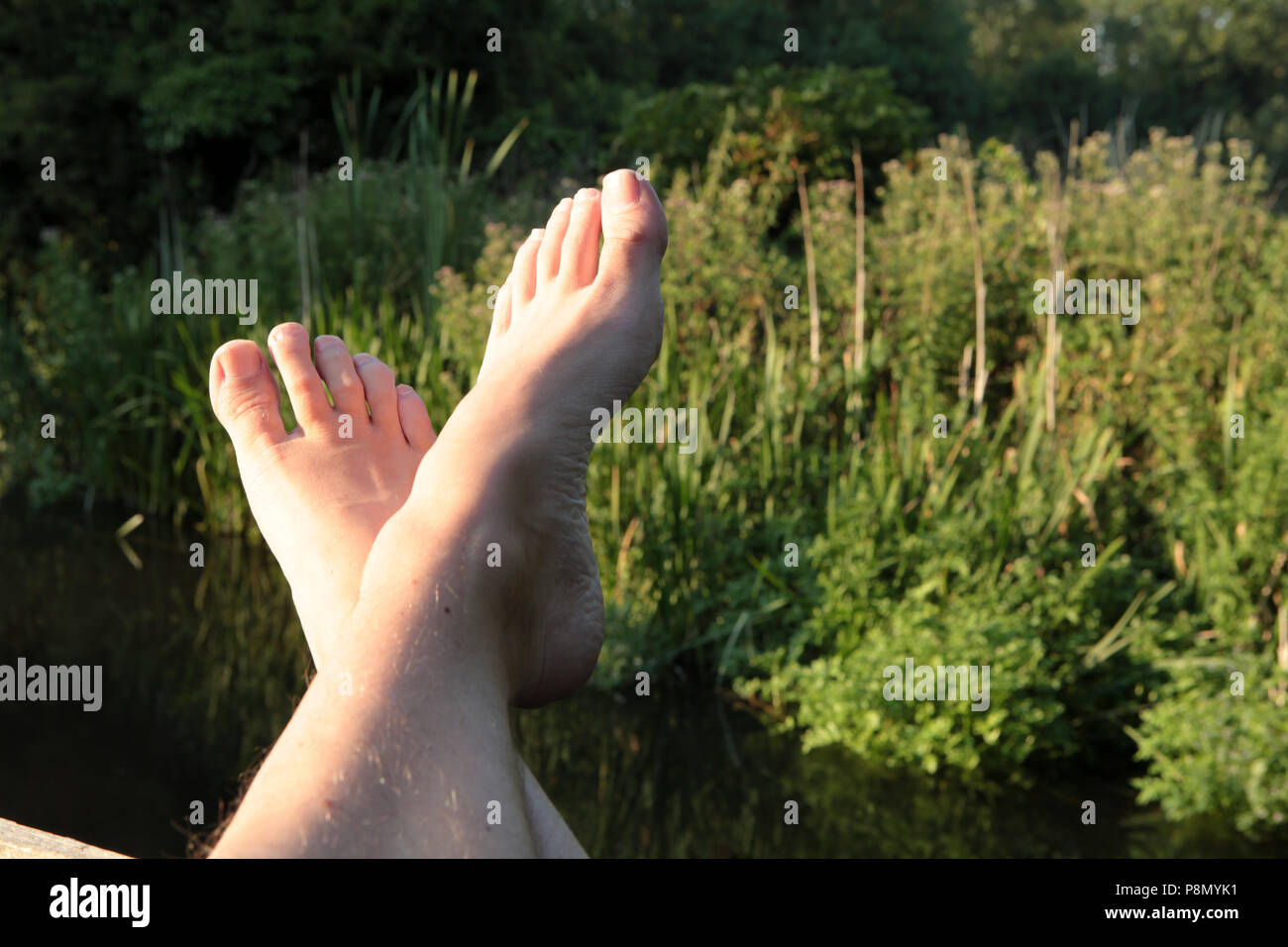 Feet up and relaxing by the river on a late summer evening in Southern England. 2018. Stock Photo