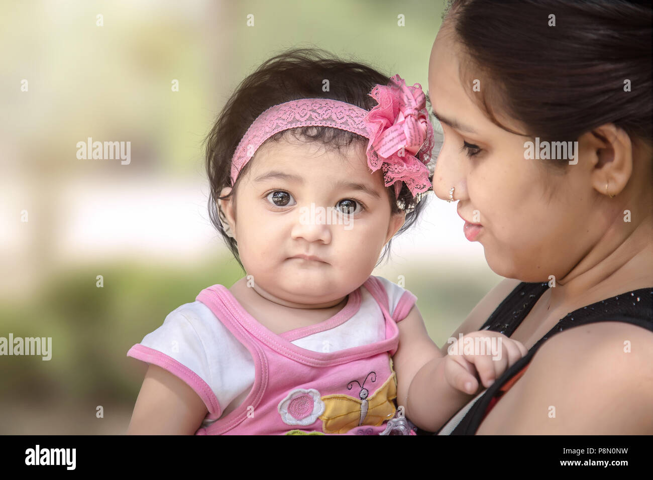 Sad Indian/Asian baby girl in mother arm. Stock Photo