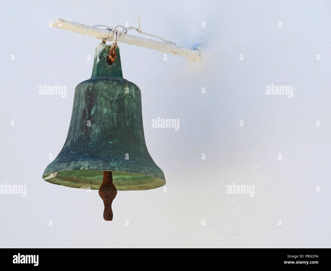 old greek metal church bell on white wall Stock Photo