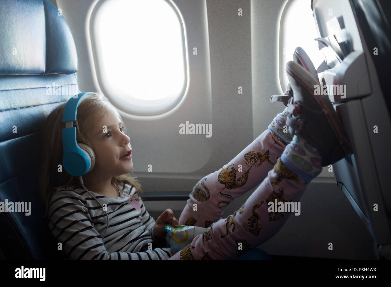 Girl wearing headphones on airplane Stock Photo Alamy
