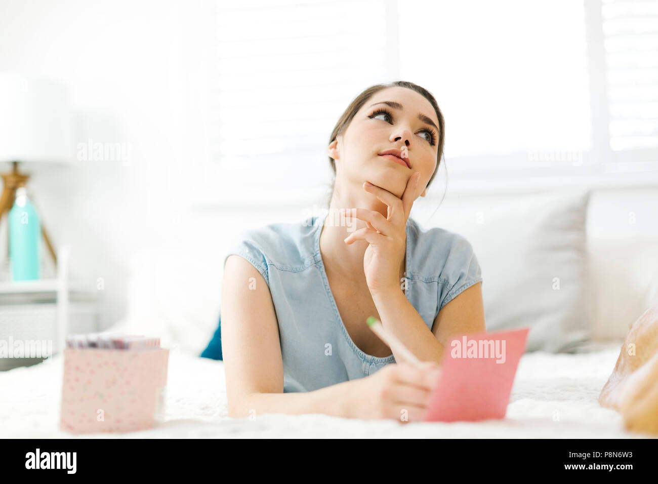 Woman writing in card on bed Stock Photo Alamy