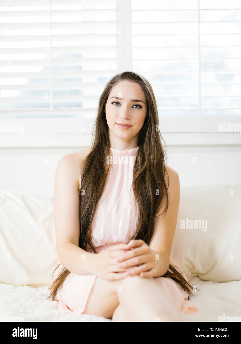 Young woman sitting on bed Stock Photo - Alamy