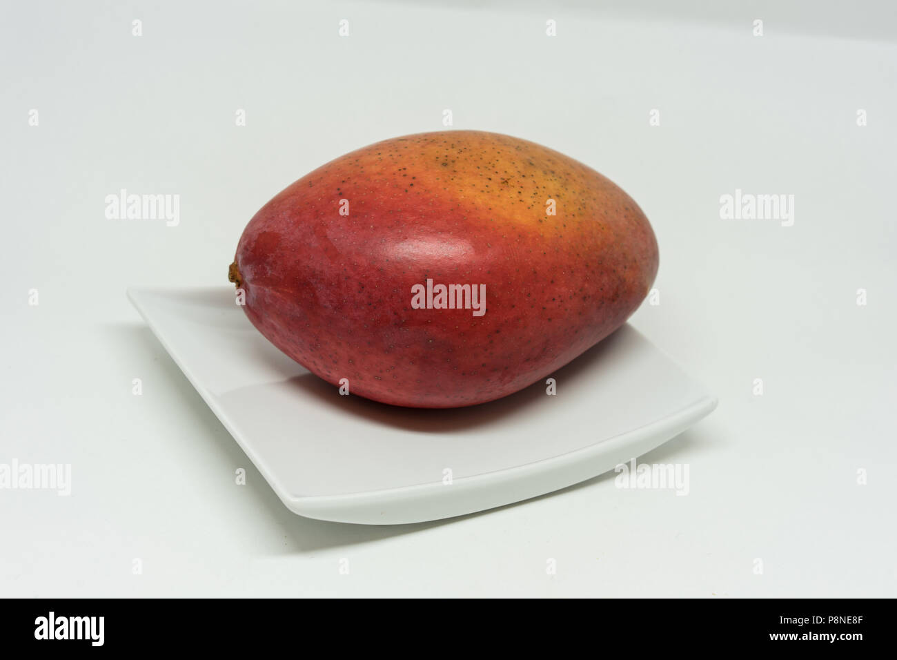 red mango fruit on plate isolated on white background Stock Photo - Alamy