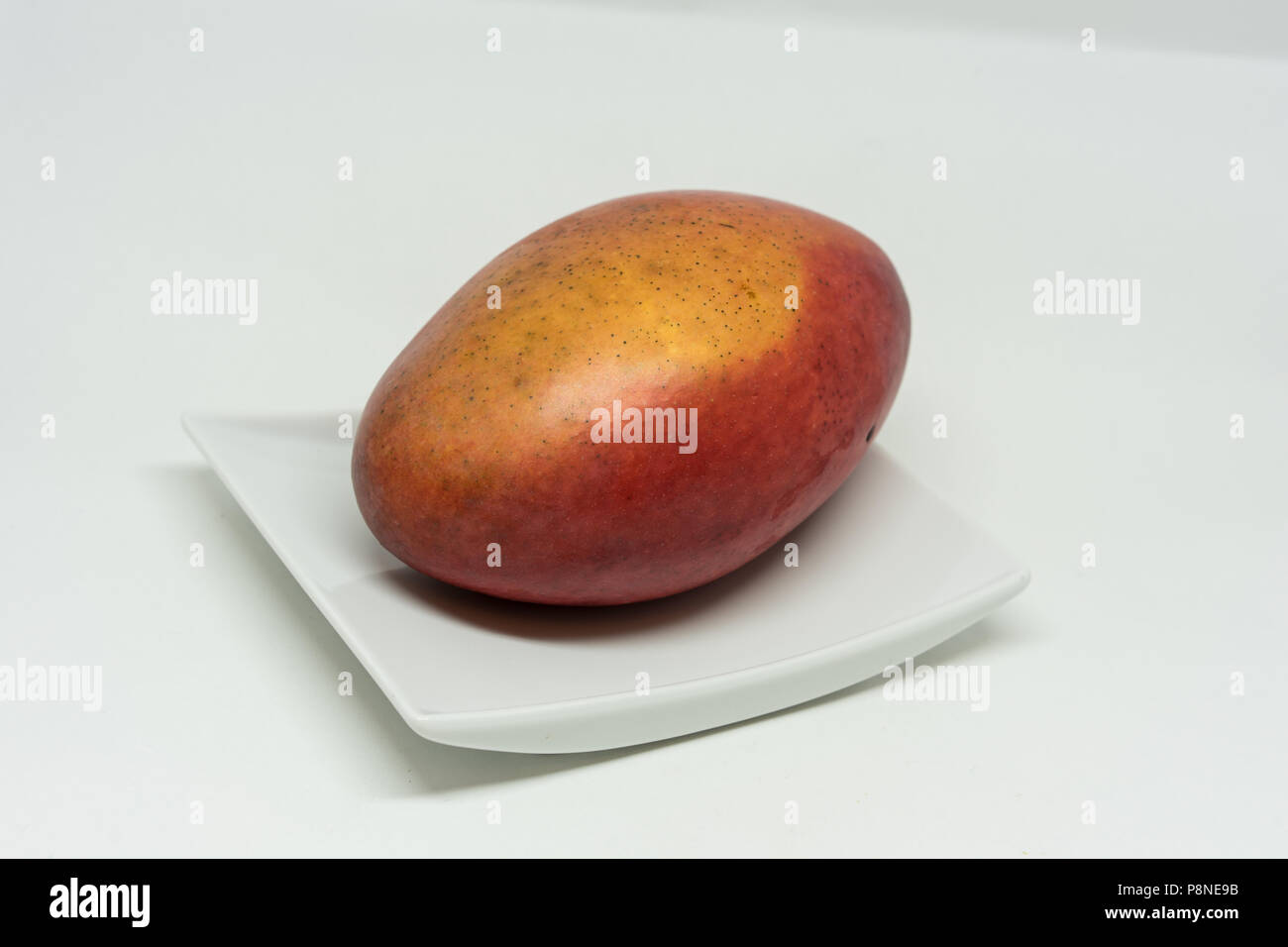 red mango fruit on plate isolated on white background Stock Photo - Alamy