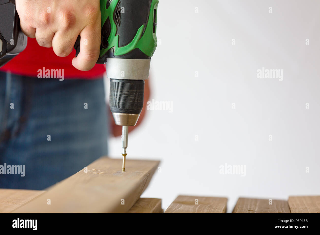 Male hand holding drilldrive while screwing screw into wood Stock
