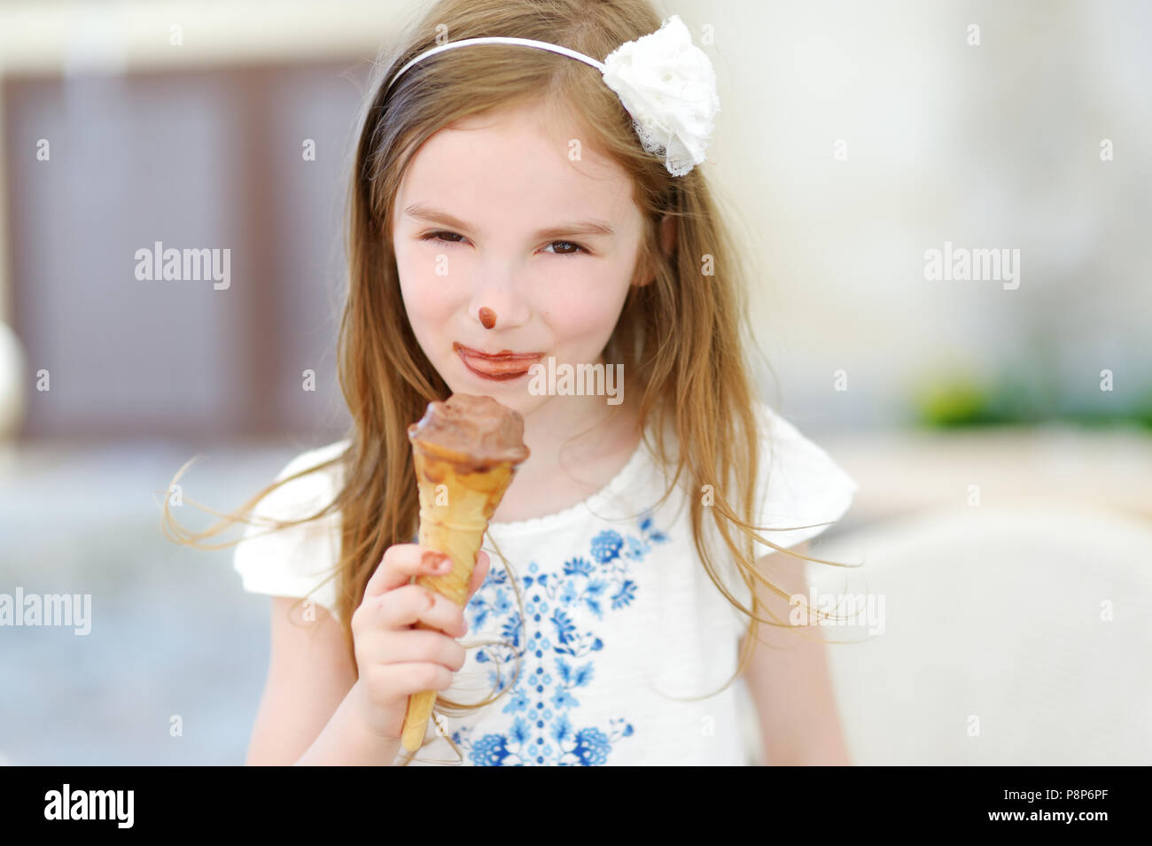 Adorable little girl eating tasty fresh ice cream outdoors on warm