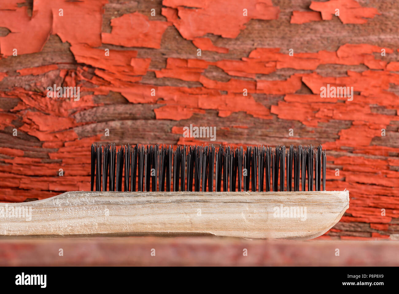 Close up view of wooden cleaning brush against old red painted background Stock Photo
