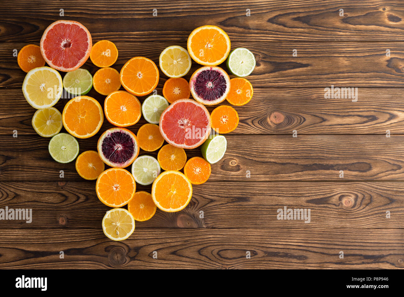 Heartshaped arrangement of citrus fruits against wooden background